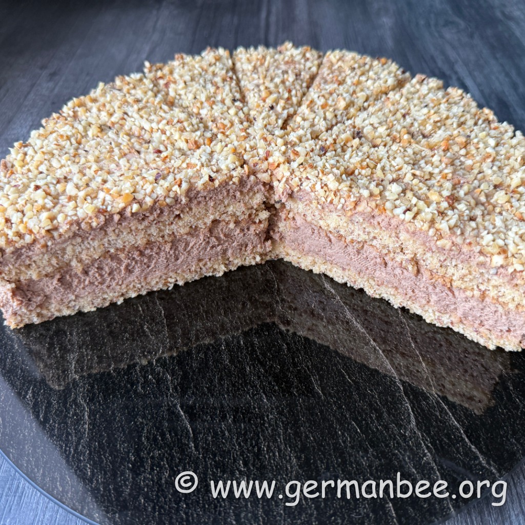 Milchfreie Nuss-Nougat-Torte mit gehackten gerösteten Haselnüssen auf einer Tortenplatte