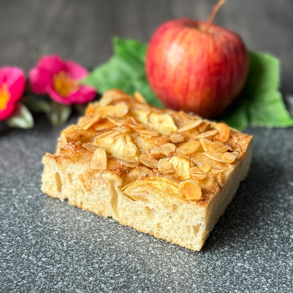 Frisch gebackene Apfel-Zimt-Focaccia vom Blech mit braunem Zucker und gehobelten Mandeln.
