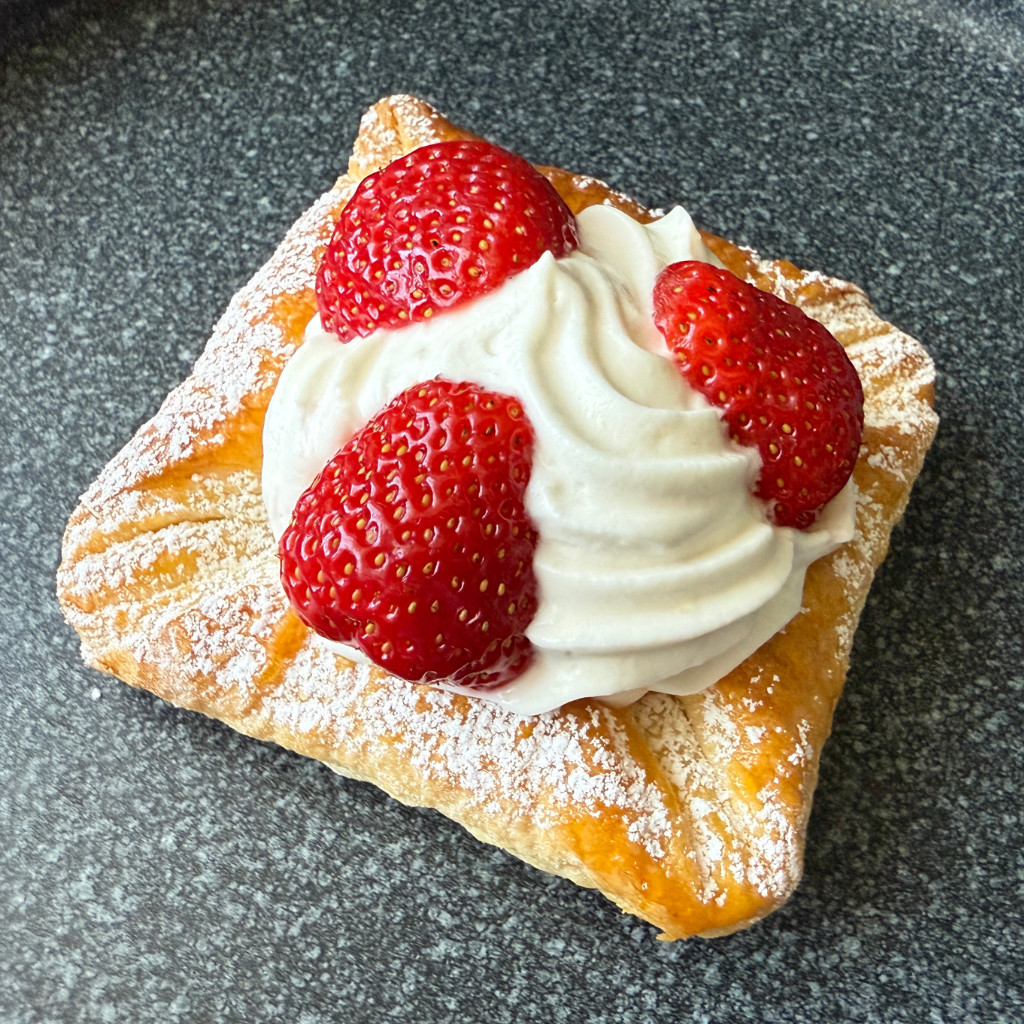 Goldbraun gebackene Erdbeerkörbchen aus Blätterteig, gefüllt mit heller Puddingsahne und garniert mit frischen Erdbeerstücken.