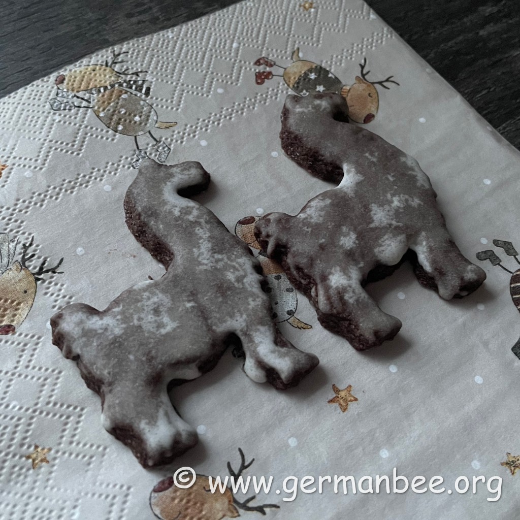 Drei Alpaka-Schokoplätzchen mit heller Zitronenglasur auf einer weihnachtlichen Serviette